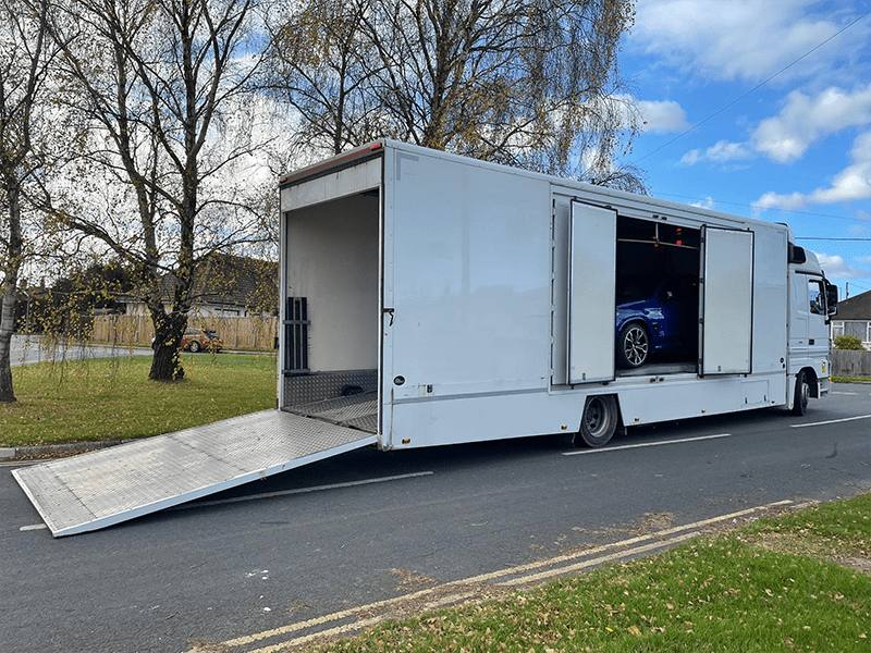 A vehicle being loaded onto a dedicated trailer